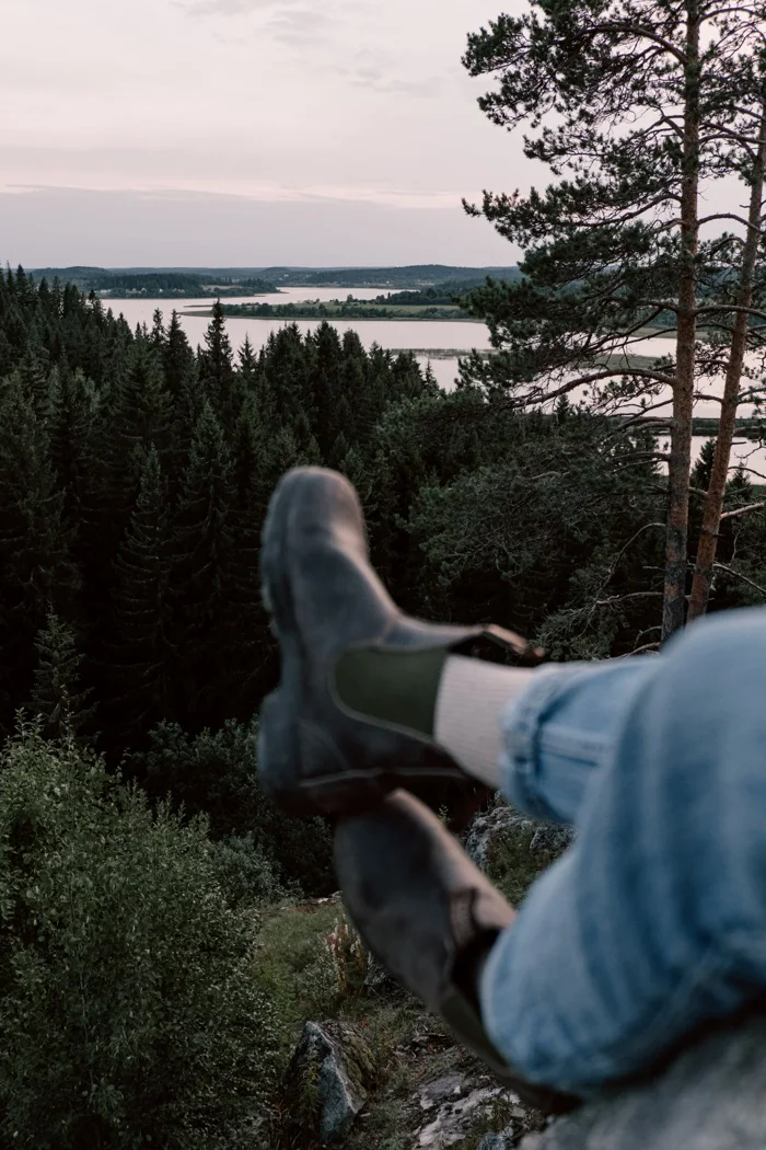Wanderschuhe vor einer bewaldeten Landschaft.