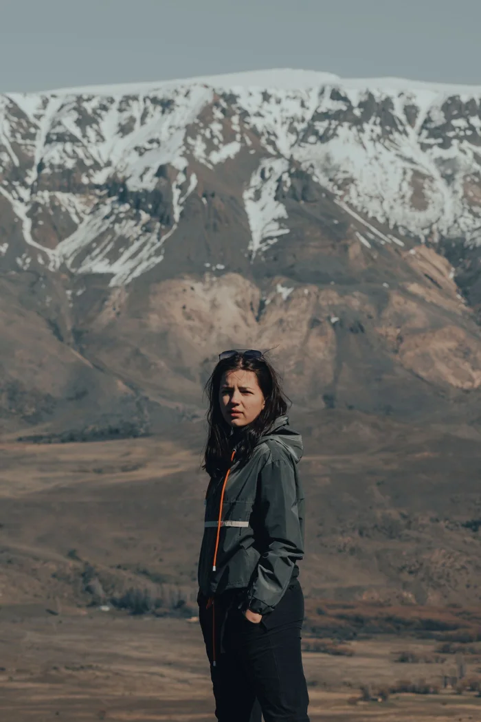 A person in a windbreaker against a mountain landscape.