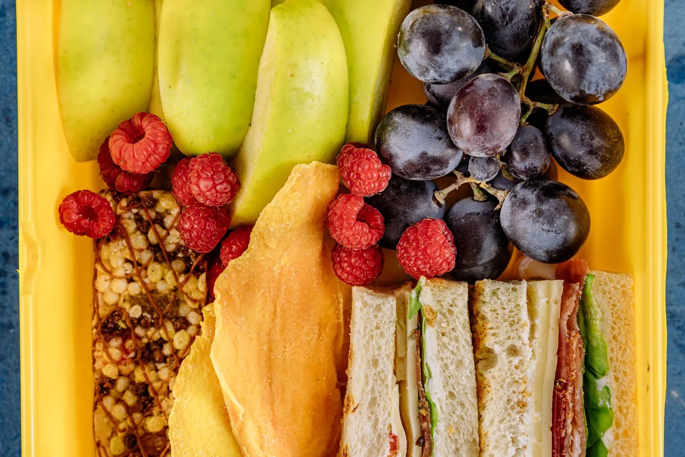 Eine geöffnete Brotdose mit Obst und Sandwich.