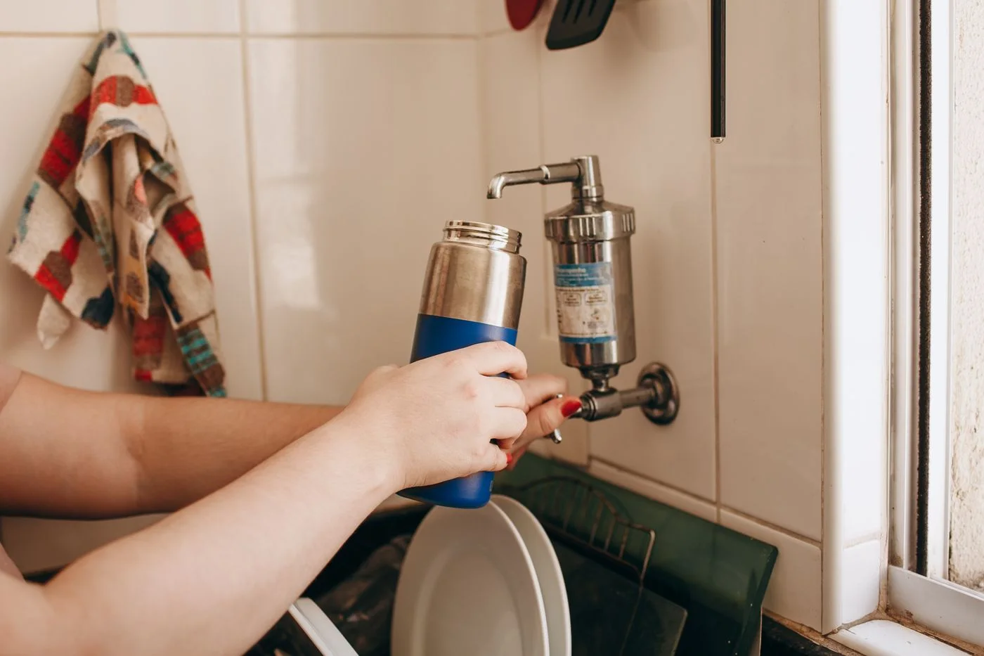 Eine Trinkflasche wird an einem Wasserhahn ausgespült.