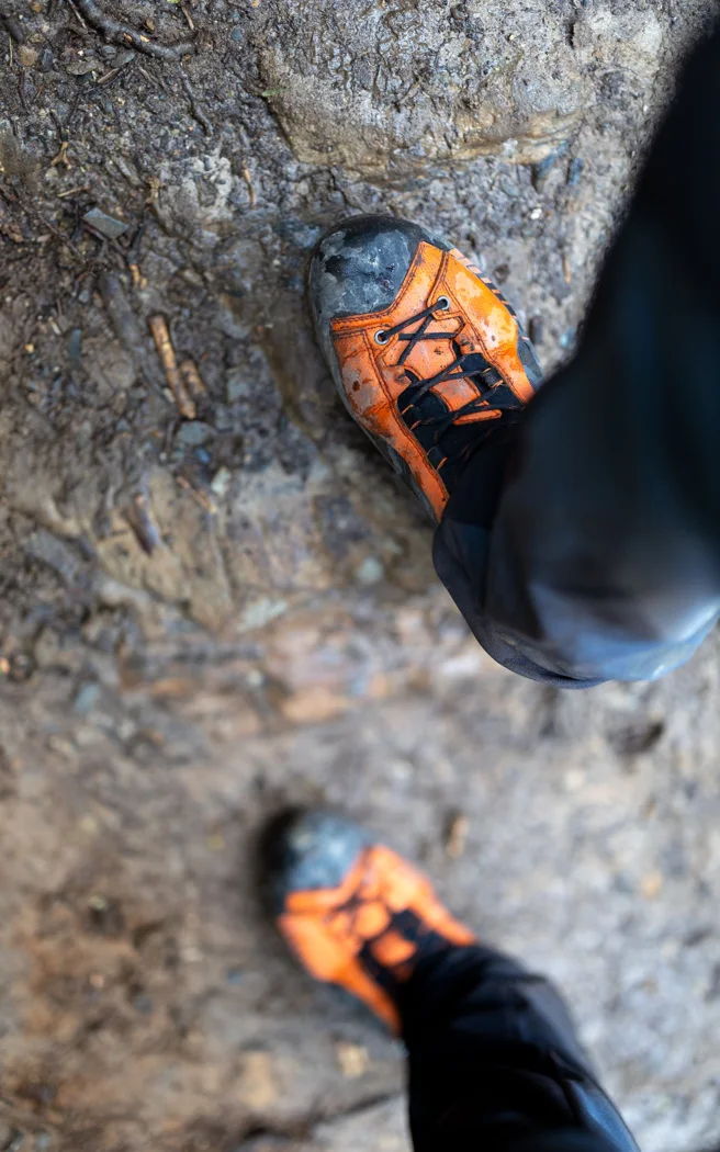 Verschmutzte Textil-Wanderschuhe auf einem Weg.