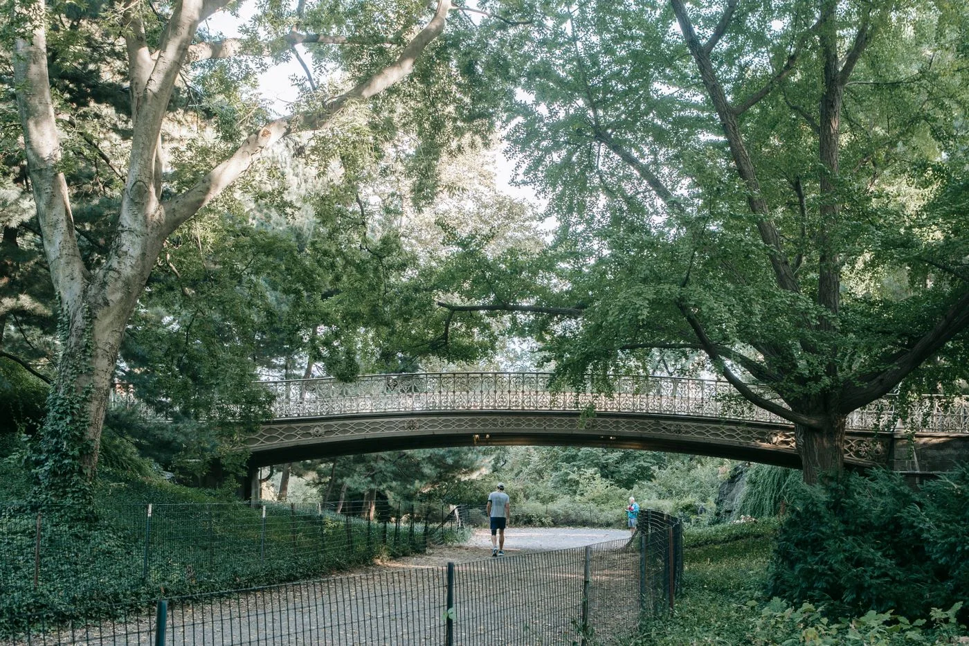 A surfaced path beneath a stone bridge.